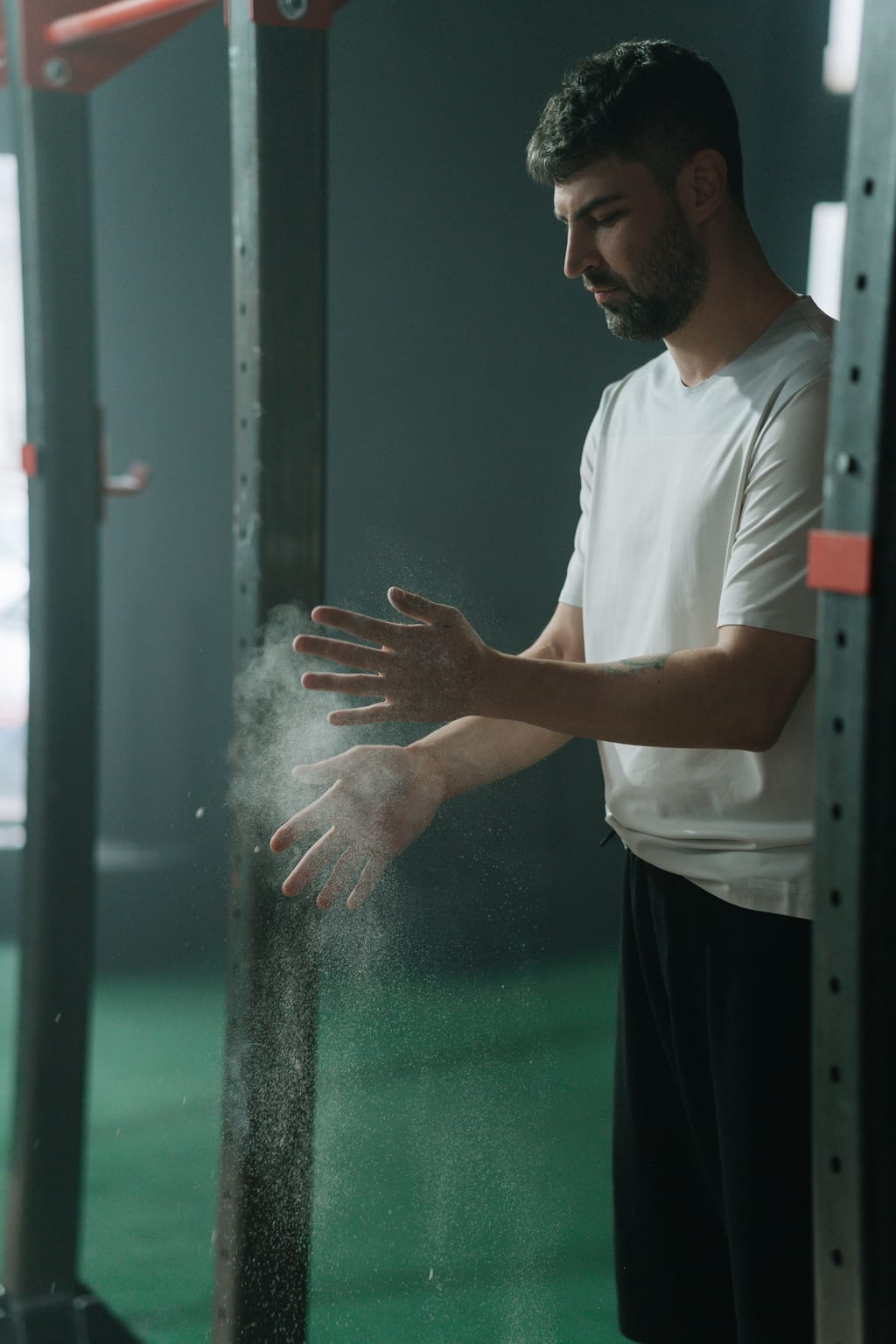 Chalk dust flies as a lifter claps their hands before a set in a dim gym